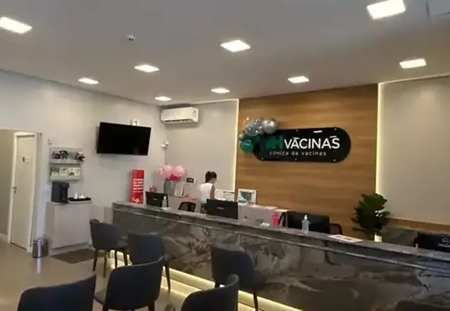 Recepção ampla da NH Vacinas com balcão de mármore escuro e logo na parede