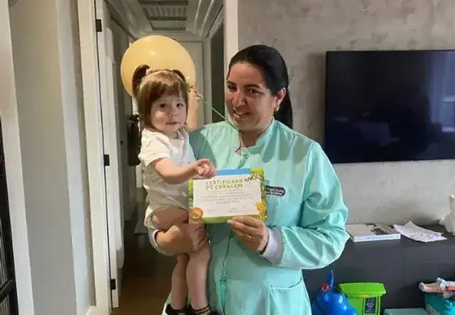 Enfermeira da NH Vacinas em atendimento domiciliar com bebê e certificado de vacinação