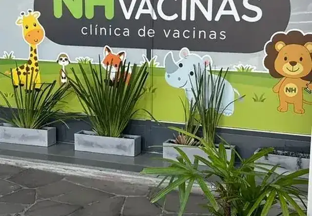 Fachada da NH Vacinas com decoração de animais e letreiro verde iluminado