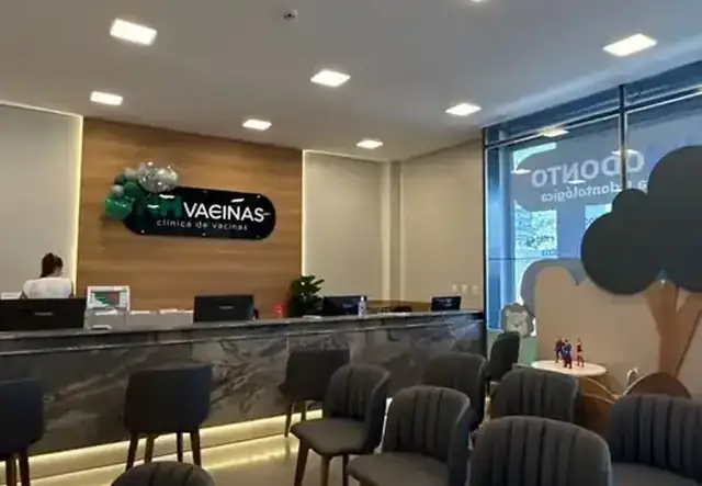 Recepção da NH Vacinas com logo, cadeiras cinza e área infantil ao fundo
